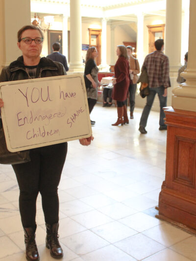 A woman holds a sign outside of the Georgia Senate chambers on March 22, 2023, following the passage of SB 140