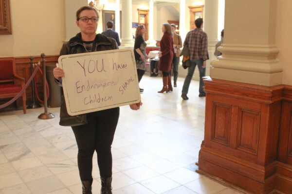 A woman holds a sign outside of the Georgia Senate chambers on March 22, 2023, following the passage of SB 140