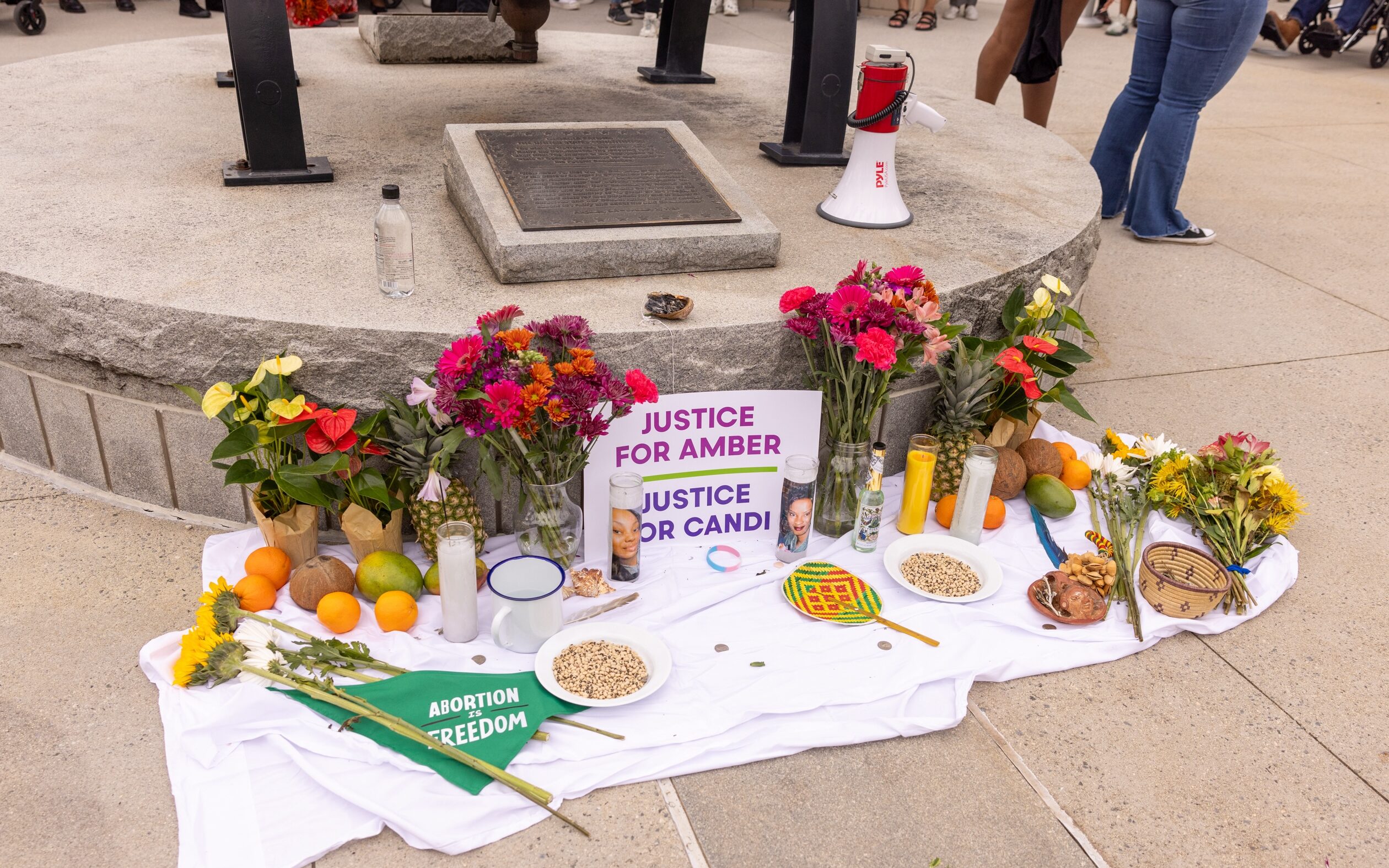 A memorial of flowers, candles, fruit, etc, and a sign that reads Justice for Amber and Justice for Candi.
