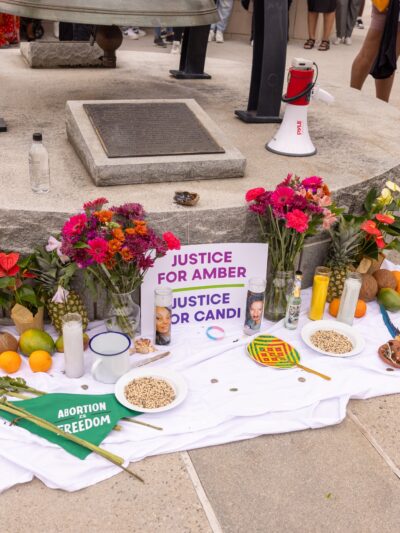 A memorial of flowers, candles, fruit, etc, and a sign that reads Justice for Amber and Justice for Candi.