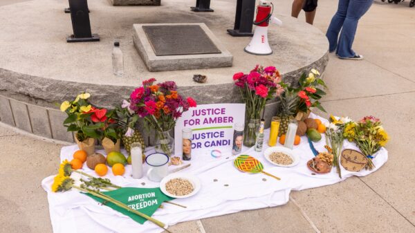 A memorial of flowers, candles, fruit, etc, and a sign that reads Justice for Amber and Justice for Candi.