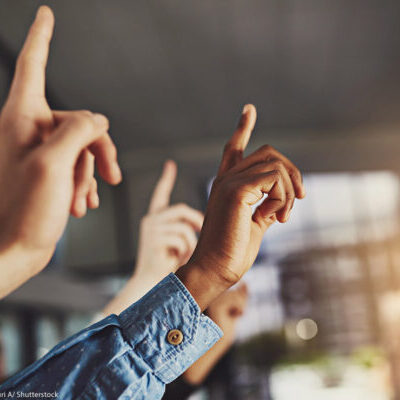 A generic image of hands pointing to the air in a classroom