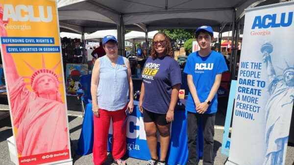 people standing in front of ACLU GA tables and signs at festival