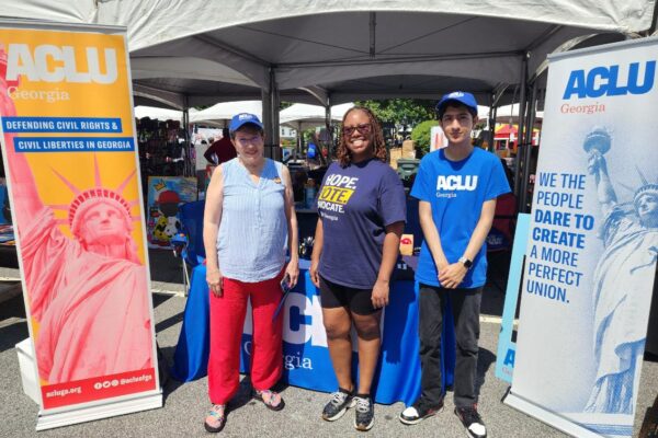 people standing in front of ACLU GA tables and signs at festival