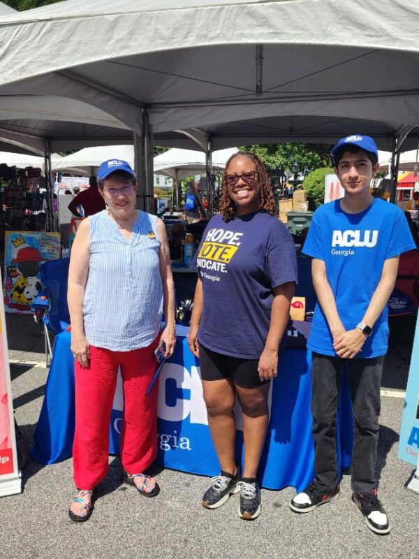 people standing in front of ACLU GA tables and signs at festival