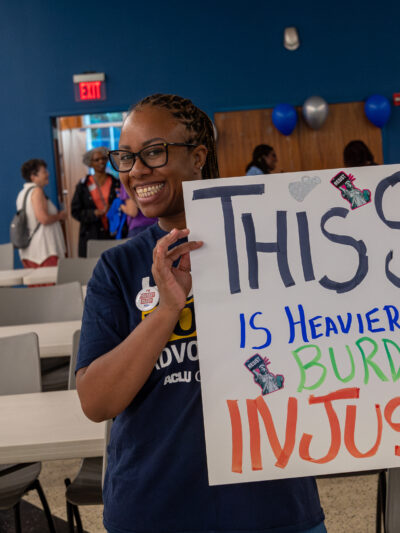 ACLU of Georgia volunteer holding sign that reads This Sign in Heavier than the burden of justice