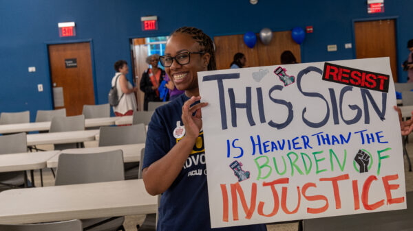 ACLU of Georgia volunteer holding sign that reads This Sign in Heavier than the burden of justice