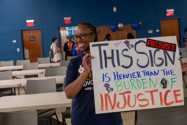 ACLU of Georgia volunteer holding sign that reads This Sign in Heavier than the burden of justice