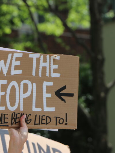 person holding sign that says we the people are done being lied to