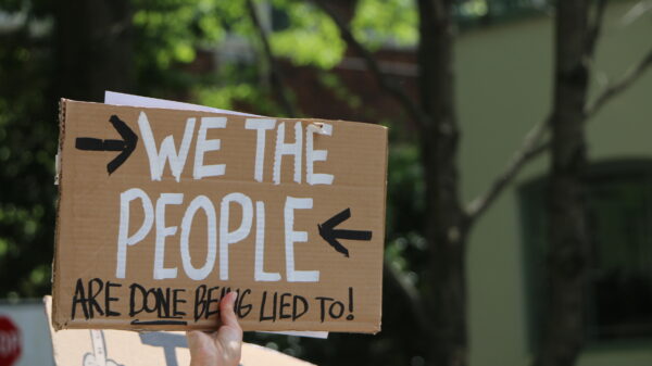 person holding sign that says we the people are done being lied to