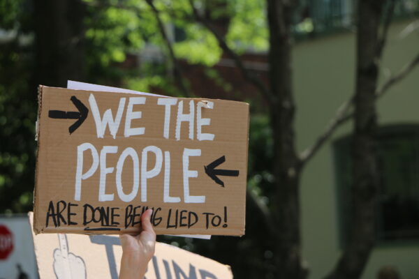 person holding sign that says we the people are done being lied to