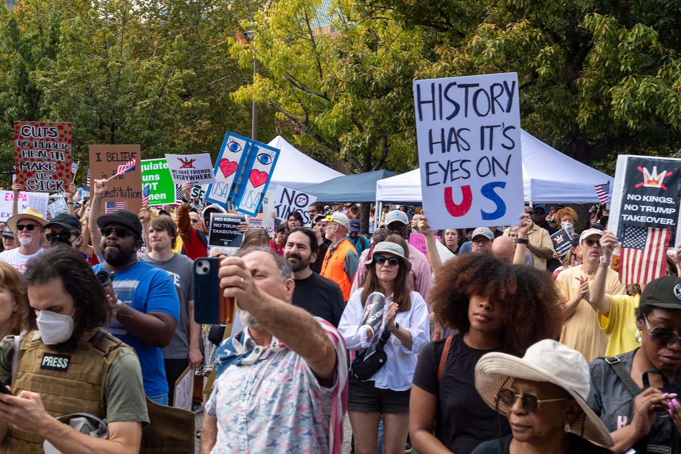 A man holds a sign above the crowd that reads History Has its Eyes on Us at the No Kings rally on October 18, 2025.