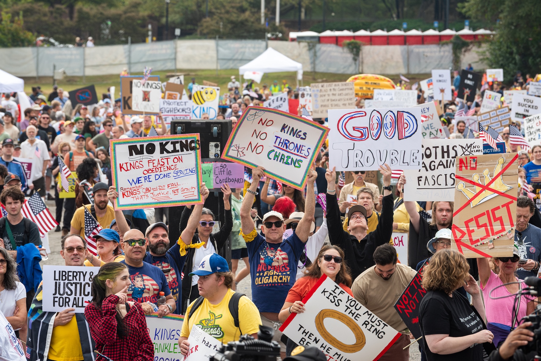 Rally goers hold signs with phrases like Good Trouble, Liberty and Justice for All and other sayings amid the crowd at the the No Kings Rally on October 18, 2025.