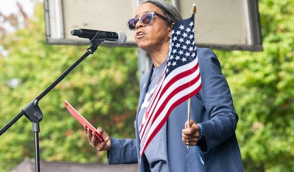 ACLU of Georgia's Executive Director Andrea Young addresses the crowd while waving an American flag at the October 18, 2025 No Kings Rally at the Atlanta Civic Center.