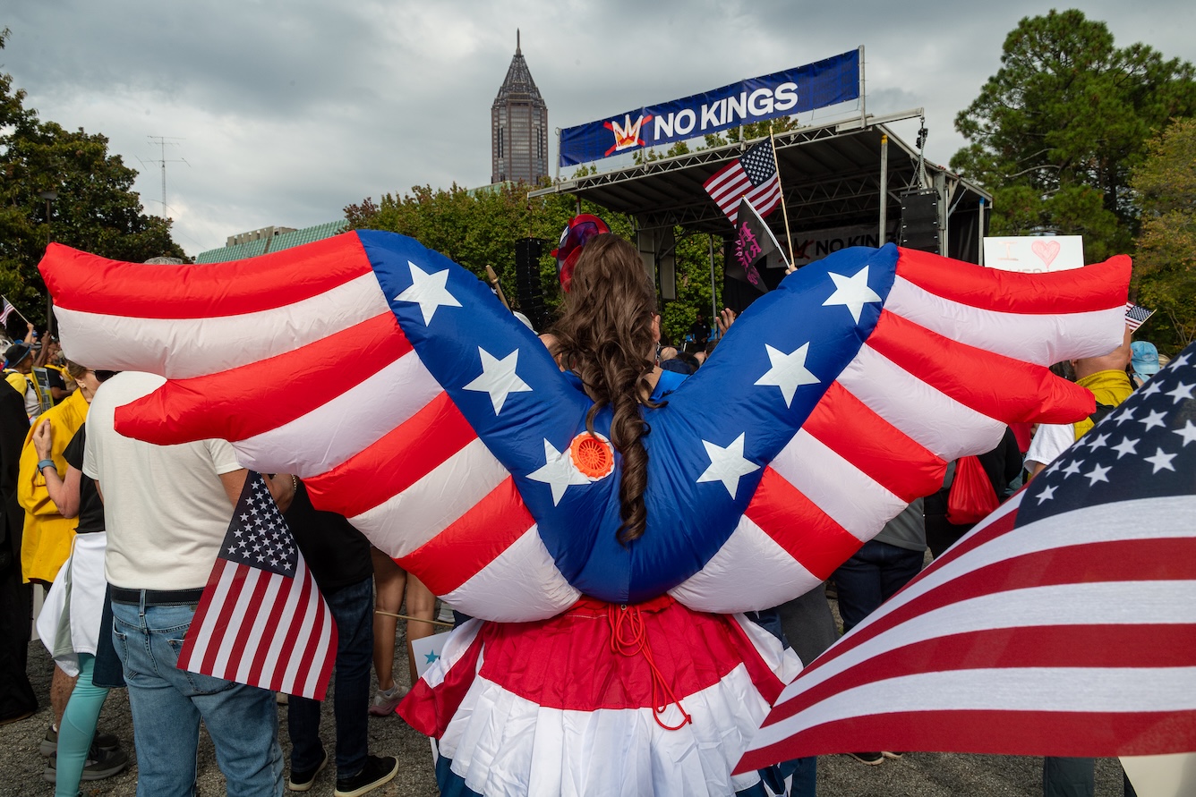 A democracy supporter in a red,white and blue patriotic inflatable costume stands near the No Kings stage at the Atlanta Civic Center on October 18, 2025.