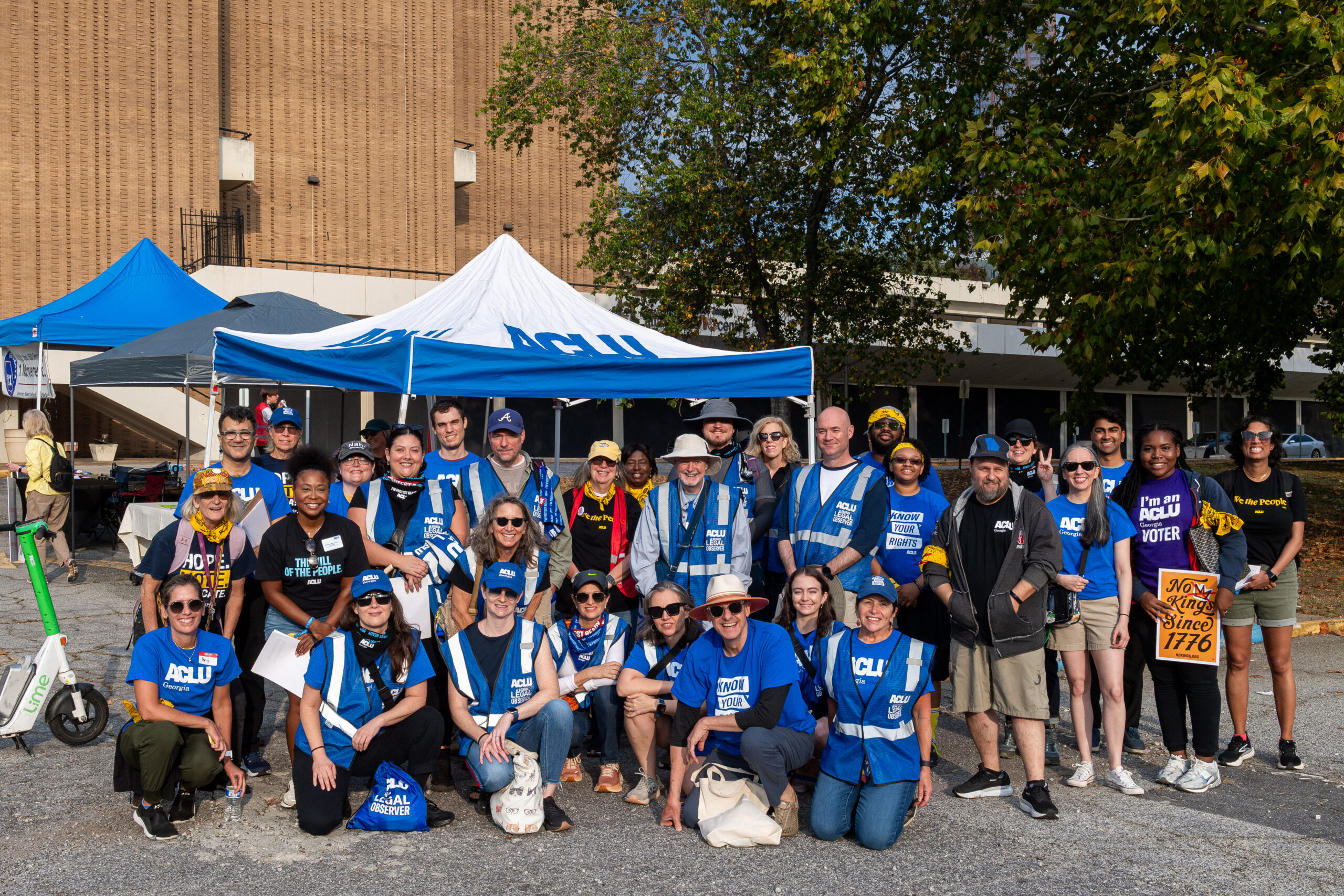 ACLU of Georgia staff, volunteers, and legal observers stand before blue and white tents at the No Kings rally at the Atlanta Civic Center.