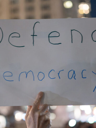 Protestor holding a sign that reads, "Defend Democracy."