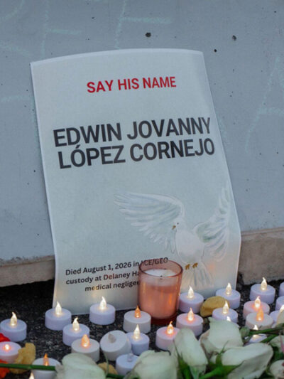 A vigil with candles in front of a sign that reads 'Say His Name: Edwin Jovanny Lopez Cornejo."