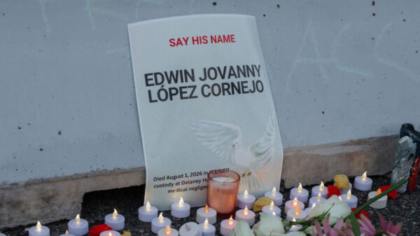 A vigil with candles in front of a sign that reads 'Say His Name: Edwin Jovanny Lopez Cornejo."