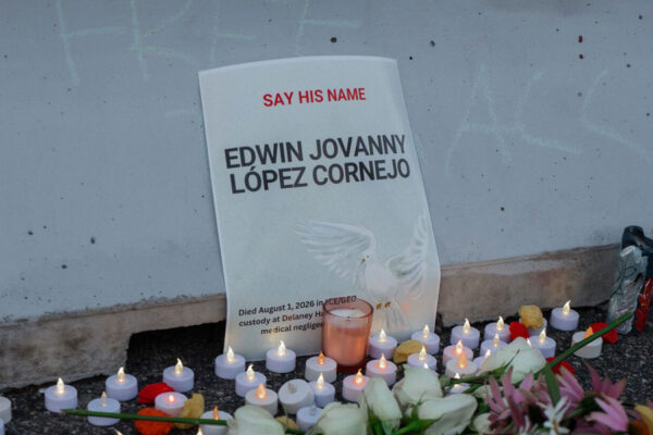 A vigil with candles in front of a sign that reads 'Say His Name: Edwin Jovanny Lopez Cornejo."