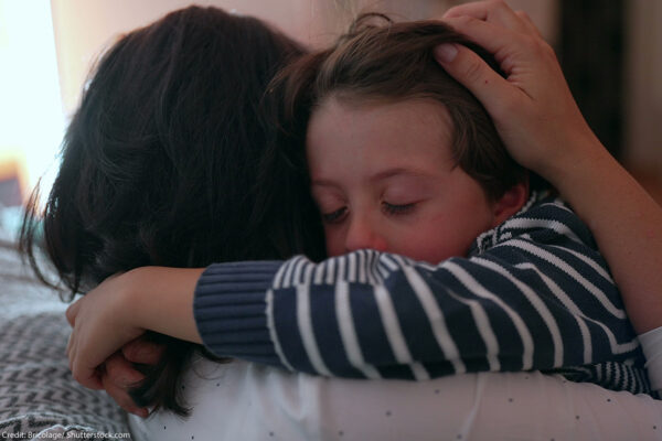 Photo of a child hugging an adult.