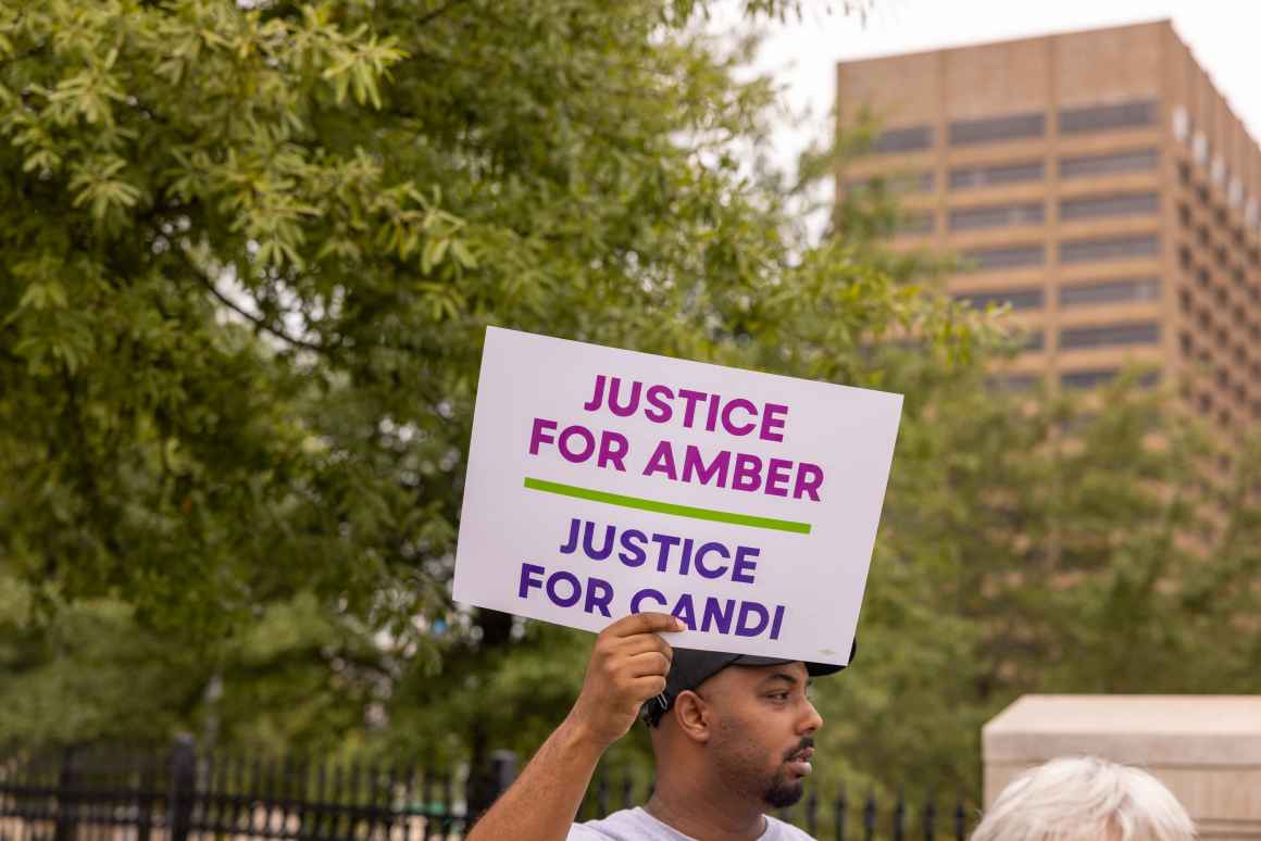 A man holds a sign that reads Justice for Amber, Justice for Candi