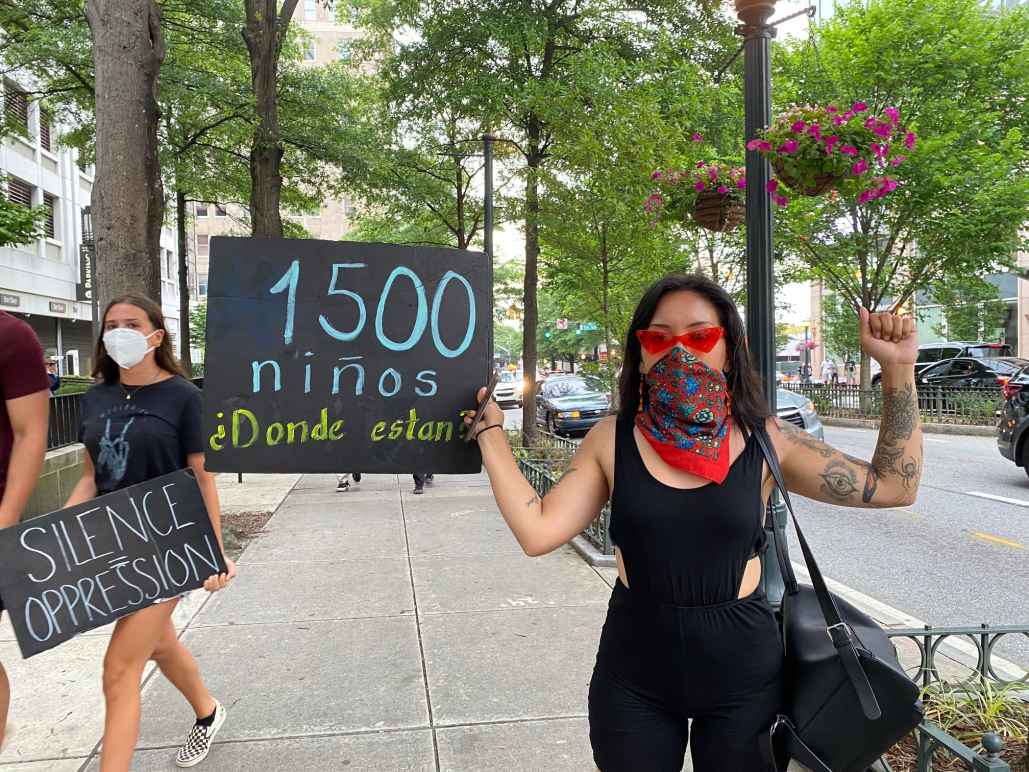 Woman protesting, holding a sign asking where the 1500 missing kids went