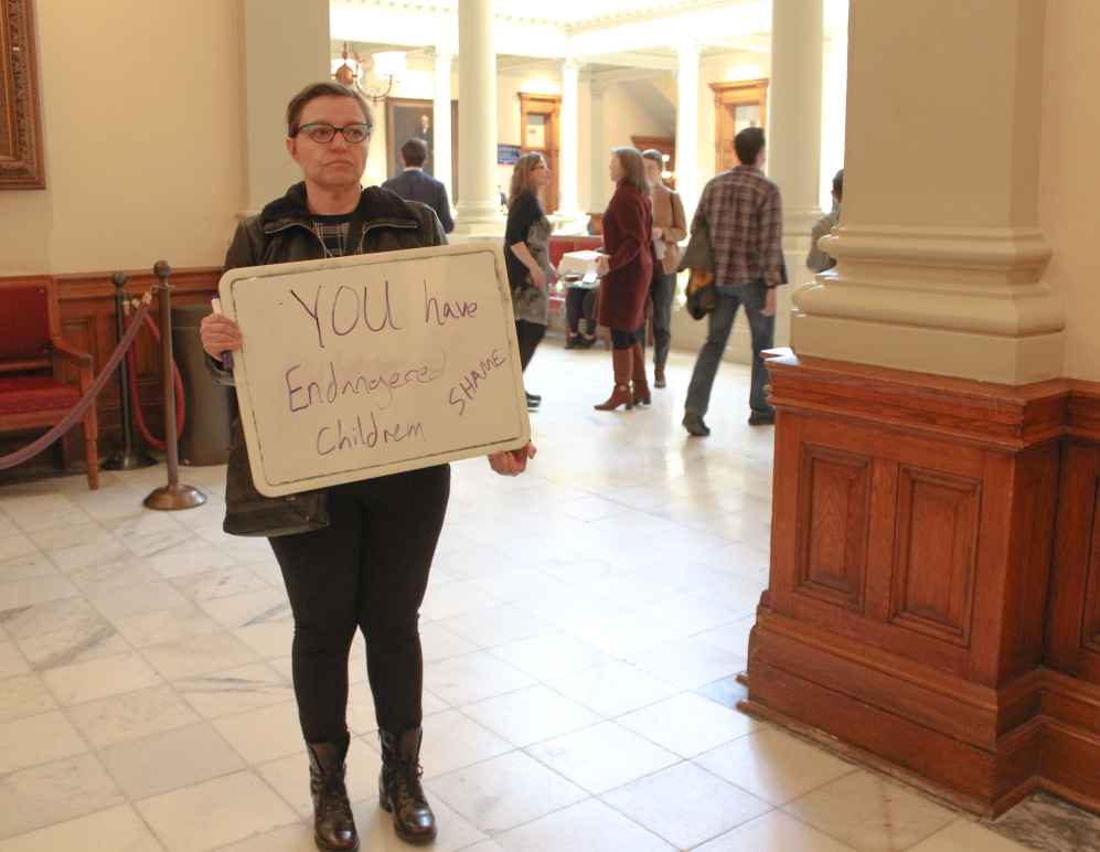 A woman holds a sign outside of the Georgia Senate chambers on March 22, 2023, following the passage of SB 140