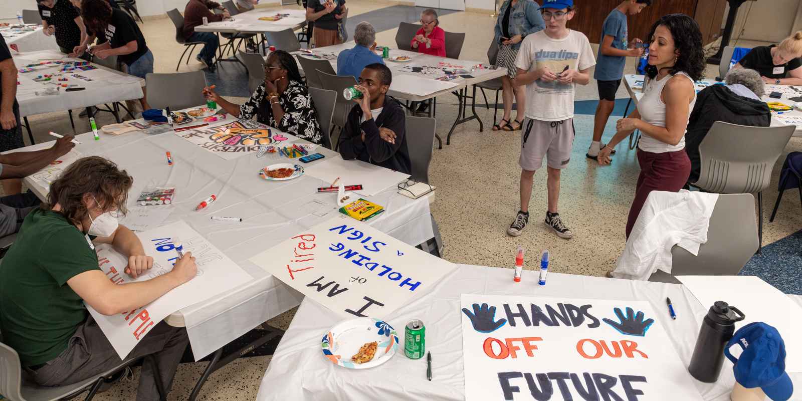 Wide shot of people gathered in room making protest signs
