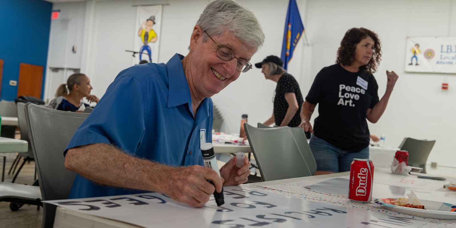 Man in blue shirt and glasses making protest sign