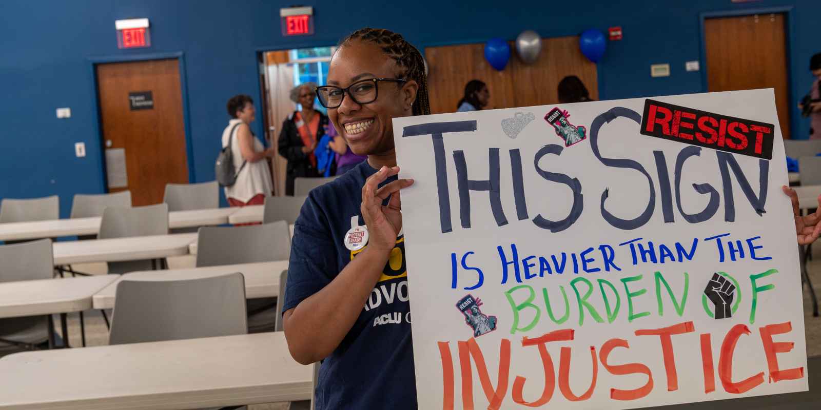 ACLU of Georgia volunteer holding sign that reads This Sign in Heavier than the burden of justice