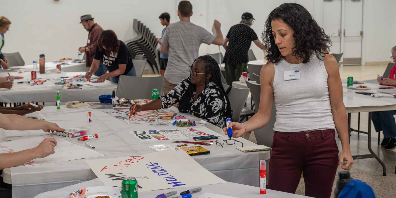 ACLU of Georgia staffer examining signs in room full of supporters making protest signs