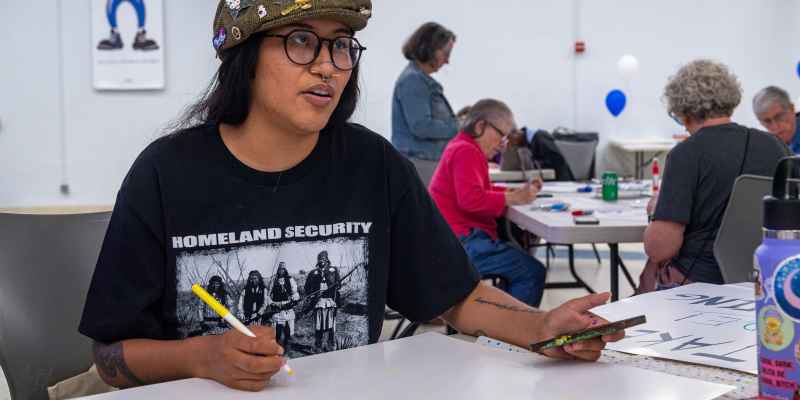 Women in black shirt and brown hat speaking across table