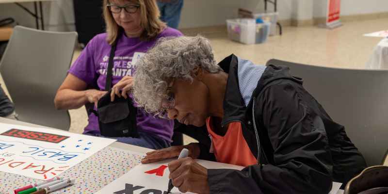 Woman making protest sign at sign making party 