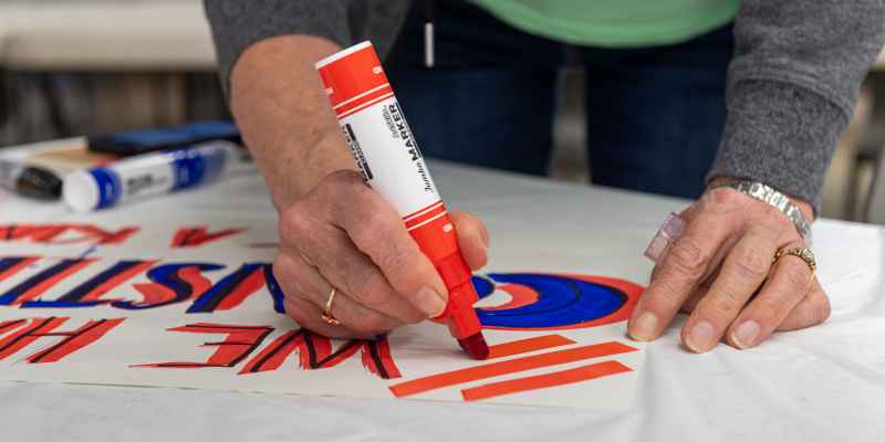 Close up of a person's hands making a protest sign with markers