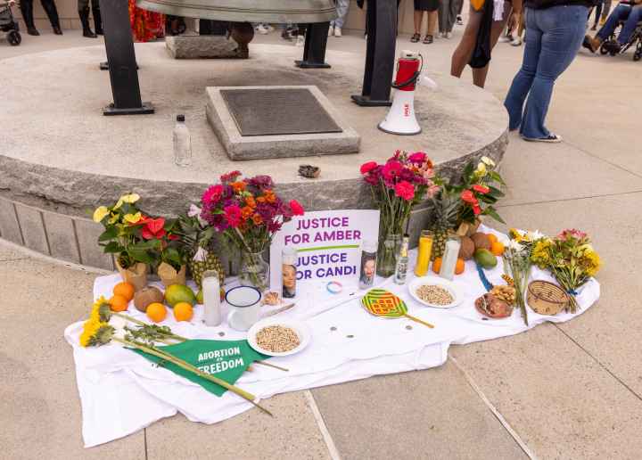 A memorial of flowers, candles, fruit, etc, and a sign that reads Justice for Amber and Justice for Candi.