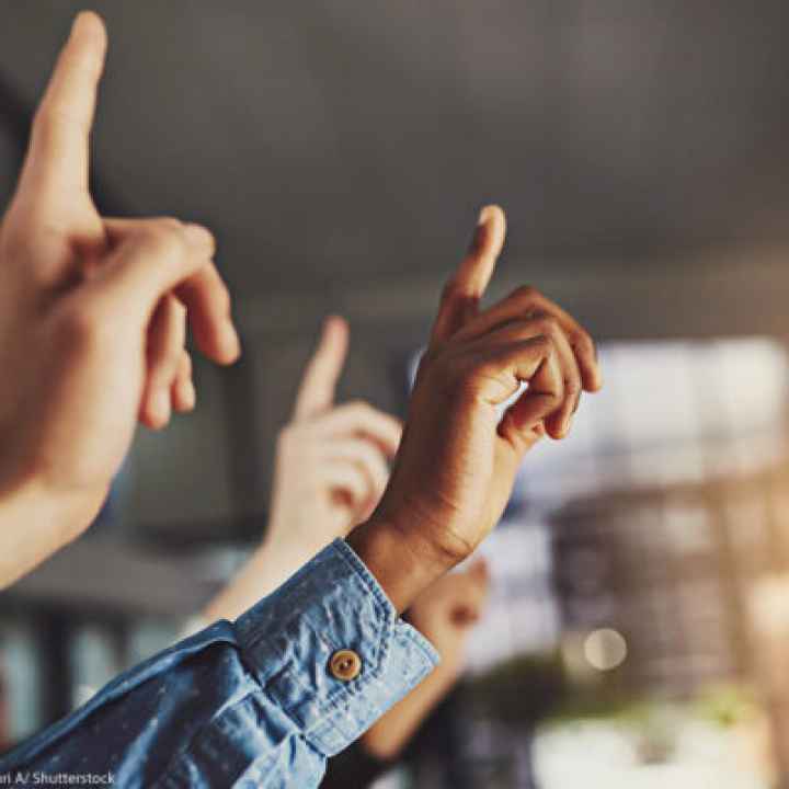 A generic image of hands pointing to the air in a classroom