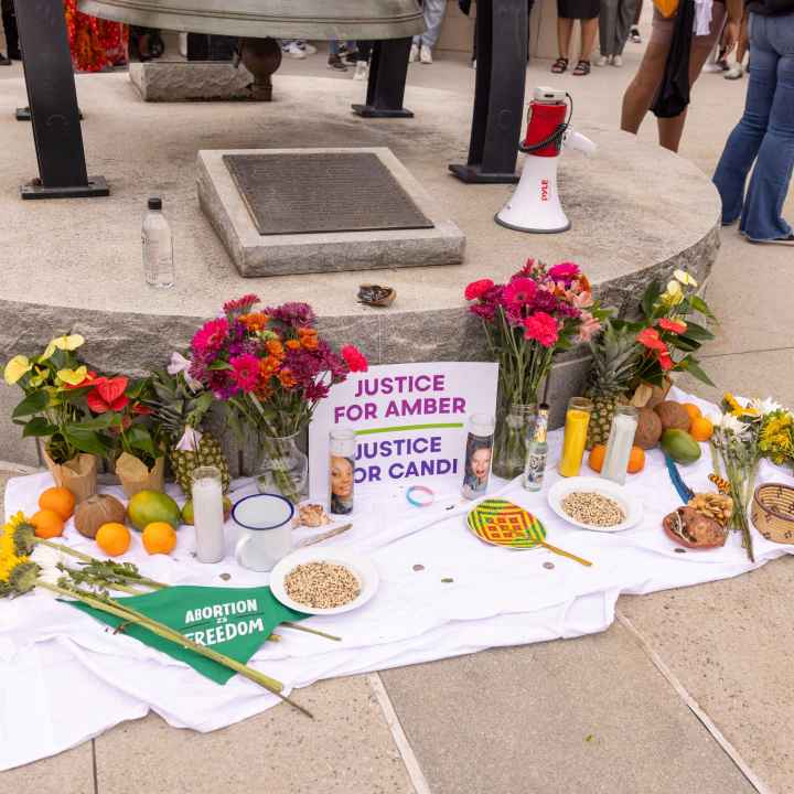 A memorial of flowers, candles, fruit, etc, and a sign that reads Justice for Amber and Justice for Candi.